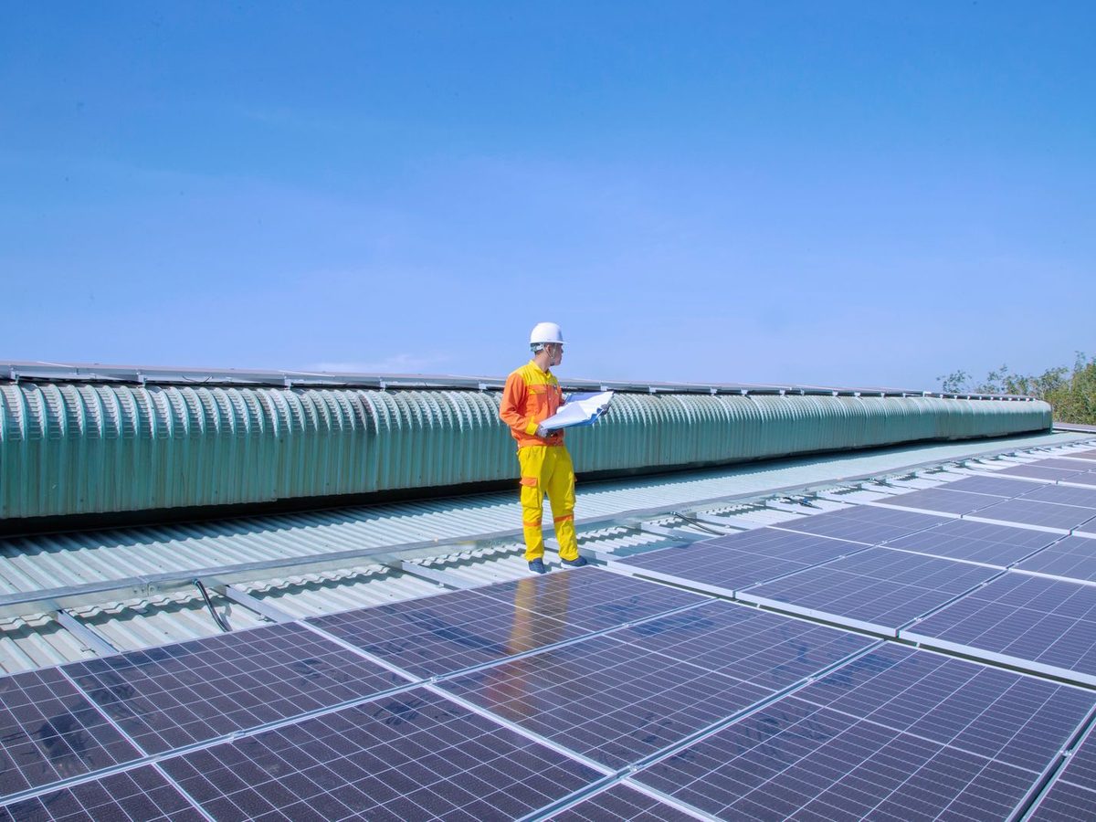 Technician inspecting solar panels on a commercial rooftop